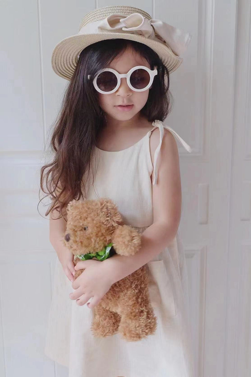 Girl standing with teddy bear, hat and sunglasses in our white sweet and breezy linen summer dress | Surfersandyogis